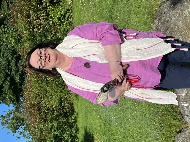 Margot Harrison in the gardens at Danu Lodge, holding a ceremonial rattle